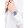A person wearing a white shirt and a silver watch with a blue face. Náhľad obrázku produktu