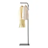 A black freestanding coat rack with a slate base, displaying a yellow dress and a cream jacket on hangers. Podgląd zdjęcia produktu