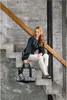 A woman sits on concrete stairs holding a leopard-print bag. Náhľad obrázku produktu