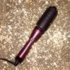 A purple GHD hair dryer brush is placed diagonally on a sparkling gold background. Produktbild-Vorschau