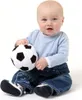 A baby sitting on a white background holding a fabric soccer ball. Produktbild-Vorschau