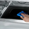 A hand is cleaning the inside of a microwave with a blue cloth. Produktbild-Vorschau