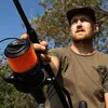 A man is holding a fishing rod with a reel attached, outdoors. Anteprima dell’immagine prodotto
