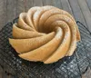A bundt cake dusted with powdered sugar sits on a cooling rack. Podgląd zdjęcia produktu