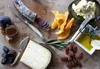 A charcuterie board with cheese, salami, figs, dates, dried mango, pecans, olive oil, and bread. Voir les images du produit