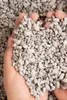 Hands holding a pile of small, light-colored pebbles. Produktbild-Vorschau