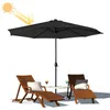 An outdoor scene with a large black umbrella, two wooden lounge chairs, and a small table with drinks. Voir les images du produit