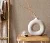 A close-up of a beige herringbone patterned wallpaper with a decorative vase and a blanket on a bamboo ladder. Produktbild-Vorschau