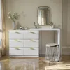 A white dresser with gold handles and a vanity table with a mirror and stool. Produktbild-Vorschau