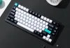 A top-down view of a mechanical keyboard on a dark surface with a white element in the upper left corner. Voir les images du produit