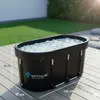 An ice bath tub filled with ice sits on a wooden deck outdoors, with a grassy lawn and bushes in the background. Anteprima dell’immagine prodotto
