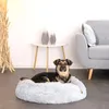 A dog is lying on a round, plush dog bed in a living room setting. Anteprima dell’immagine prodotto