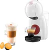 A white Krups Dolce Gusto coffee machine with a cup of coffee and two coffee capsules. Produktbild-Vorschau