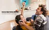 A couple is enjoying themselves on a couch, with the woman holding a microphone and wearing headphones, while the man laughs. Produktbild-Vorschau