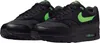 A pair of black Nike Air Max 1 Essential sneakers with green accents. Produktbild-Vorschau