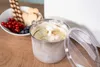 Die Unold EISMASCHINE Doppio 2,4 L, gefüllt mit Vanilleeis, steht offen auf einer Holzplatte. Danebe Produktbild-Vorschau