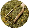 A close-up view of dried yerba mate leaves and yellow flower petals in a wooden scoop, with more of the mixture filling the frame. Voir les images du produit