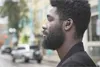 A man wearing earbuds in a city street. Anteprima dell’immagine prodotto