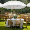 An outdoor wedding reception setup with tables and chairs under a large white umbrella. Produktbild-Vorschau