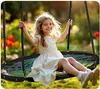 A young girl is happily swinging on a large nest swing in a garden setting. Podgląd zdjęcia produktu