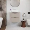 A modern bathroom vanity with a vessel sink, a round mirror, and a wooden stool with a bottle on it. Náhled obrázku produktu