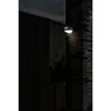 An outdoor wall light is mounted on a brick pillar next to a dark wooden fence. Produktbild-Vorschau