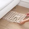 Beiger Kunststoff-Unterbett-Aufbewahrungsgitter, das von zwei Händen unter ein weißes Sofa geschoben wird Anteprima dell’immagine prodotto