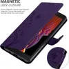 A purple flip case for a smartphone, with floral patterns, is shown open, revealing the phone screen. A close-up inset shows the magnetic clasp detail. Náhled obrázku produktu