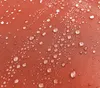 Close-up of water droplets on an orange fabric surface. Produktbild-Vorschau