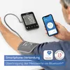 A person's arm is connected to a blood pressure monitor, which is also connected to a smartphone displaying the same readings. Podgląd zdjęcia produktu