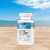 A bottle of OstroVit Marine Collagen supplement sits on a sandy beach with the ocean and sky in the background. Náhľad obrázku produktu