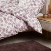 A close-up view of a bed with patterned bedding and a bedside table with candles. Produktbild-Vorschau