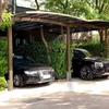 Two cars parked under a carport with lush green foliage surrounding them. Náhled obrázku produktu