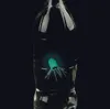 A glowing, turquoise jellyfish-like object with tentacles is inside a clear plastic bottle against a black background. Produktbild-Vorschau