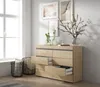 A modern bedroom scene featuring a wooden dresser with open drawers, decorative vases with branches, and framed artwork on the wall. Produktbild-Vorschau