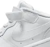 A close-up view of a white Nike shoe, focusing on the velcro strap and the Nike swoosh logo. Voir les images du produit