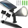 A solar-powered LED spotlight with accessories, including stakes and mounting hardware, displayed on a white background. Voir les images du produit