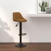 A brown velvet bar stool with a black base and adjustable height is shown against a white wall and wooden floor. Produktbild-Vorschau