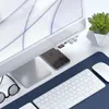 A desk setup with an iMac, a Satechi USB-C hub attached to the iMac, a smartphone, a keyboard, a mouse, and a pair of glasses. Produktbild-Vorschau