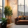 A modern living room with a large window overlooking a city skyline, featuring a brown leather sofa and a tall floor lamp with a circular top light and a smaller reading light. Voir les images du produit