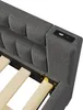 A close-up view of the headboard of a gray upholstered bed frame, showing a built-in USB charging port. Produktbild-Vorschau