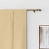 A close-up view of a beige curtain hanging from a curtain rod. Voir les images du produit