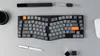 A top-down view of a split ergonomic keyboard and accessories on a gray surface. Produktbild-Vorschau
