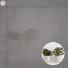 A close-up of grey shade cloth with a grommet in the corner and a small inset image of two potted plants. Produktbild-Vorschau