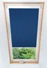 A dark blue roller blind is installed in a slanted attic window, with green trees visible outside. Produktbild-Vorschau