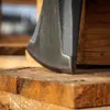 A close-up shot of an axe head resting on wooden planks. Náhled obrázku produktu