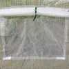 Close-up view of a greenhouse cover with a transparent window, showing grass and soil outside. Produktbild-Vorschau