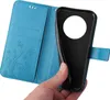 A hand is holding a blue flip phone case open, revealing the inside with card slots and a floral embossed design. The phone itself is partially inserted into the case. Produktbild-Vorschau