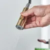 A hand is holding a pull-down kitchen faucet sprayer, with water spraying out. Náhľad obrázku produktu