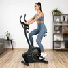 A woman is exercising on a stationary bike in a home gym setting. Náhľad obrázku produktu